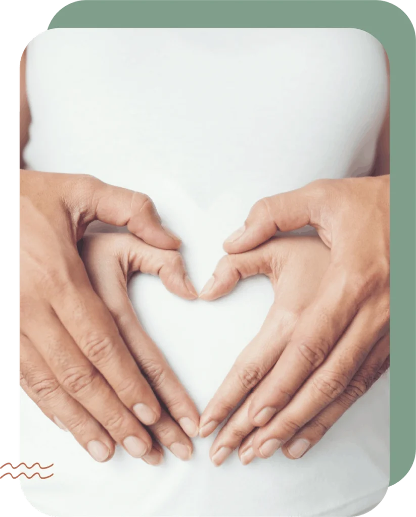 par drži ruke i oblikuje srce na trudničkom trbuhu